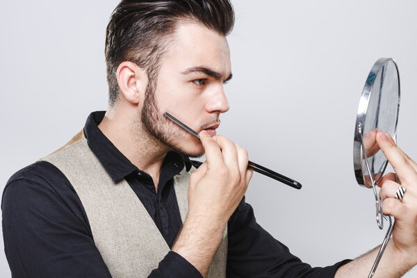 Молодой человек бреется у зеркала
