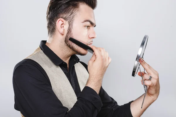 Joven hombre brutal peinándose la barba — Foto de Stock