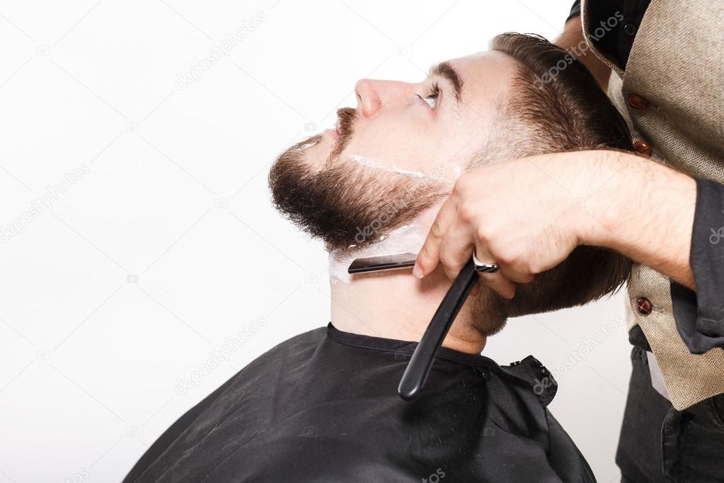 Hairdresser shaving handsome man