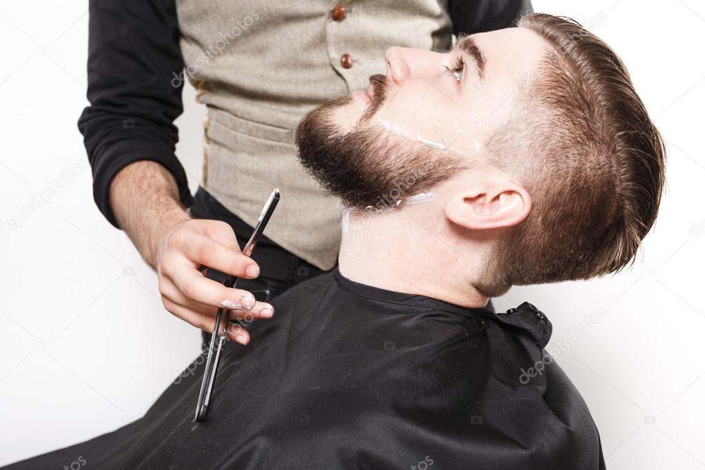 Hairdresser shaving young customer