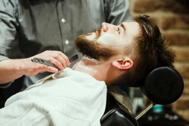 Barber shaving a bearded man clipart
