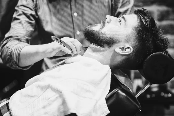 Barber shaving a bearded man — Stock Photo, Image