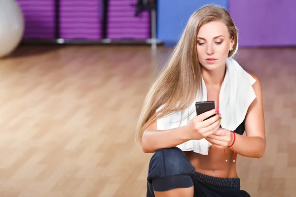 Hübsches Mädchen mit Telefon in der Turnhalle — Stockfoto