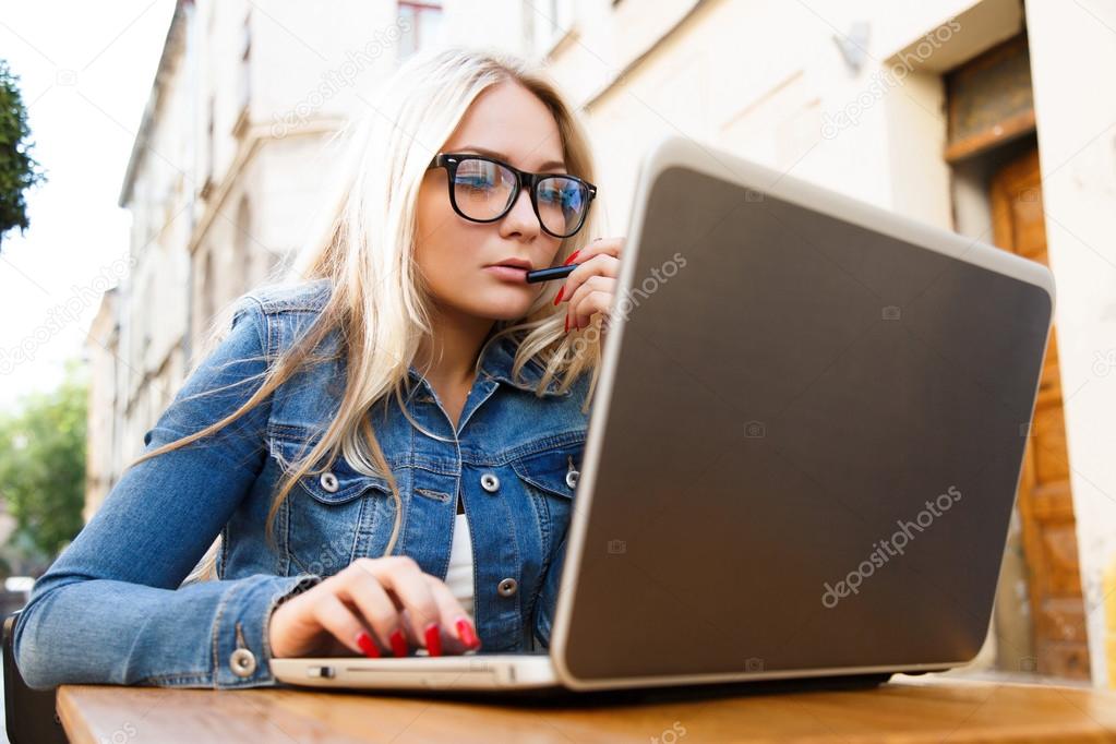Blond woman working with laptop on the street