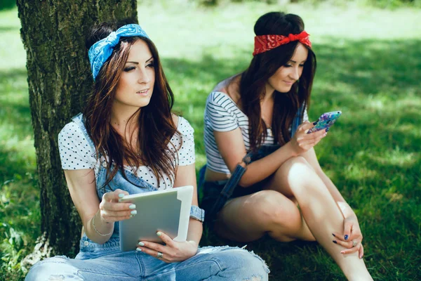 Дівчата близнюки з планшетом і мобільним — стокове фото