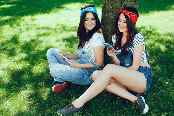 Gêmeos meninas com gadgets no parque — Fotografia de Stock