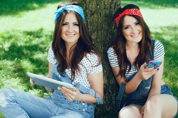 Happy twins girls sitting in the park. - Stok İmaj