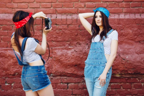 Twins girl taking photo on brick wall — Stock Photo, Image