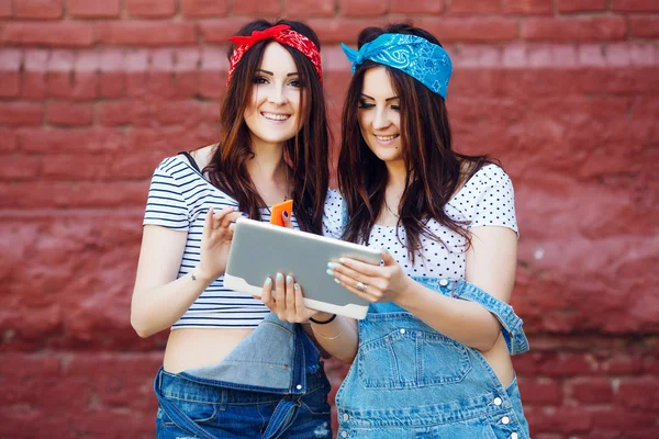 Brunette twins girls with tablet — Stockfoto