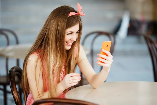 Дівчина посміхається і дивиться на мобільний телефон — стокове фото