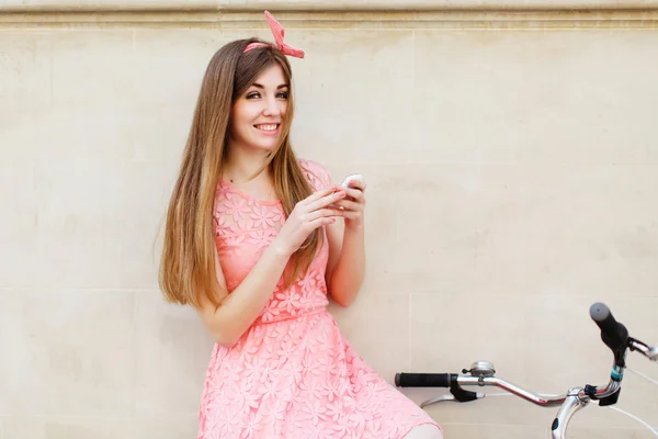 Дівчина посміхається і тримає смартфон — стокове фото
