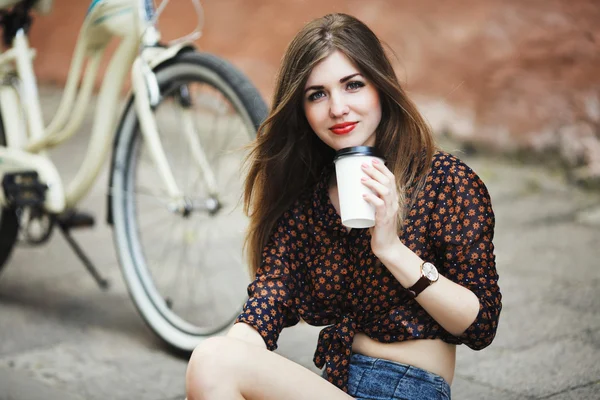 Κορίτσι του θέτουν με καφέ στο πλακόστρωτο πεζοδρόμιο στην παλιά πόλη — Φωτογραφία Αρχείου