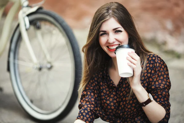 Chica sonriente está tomando café en pavimento de baldosas en la ciudad vieja — Foto de Stock