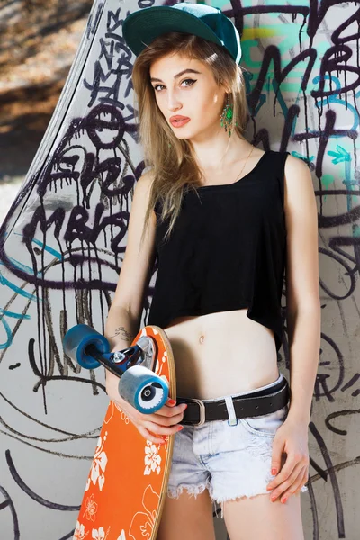 Mujer joven posando con tabla de skate —  Fotos de Stock