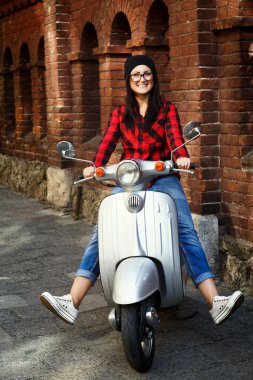 Stylish woman posing on a vintage scooter