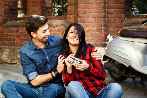 Smiling couple hugging on the pavement, girl is holding camera — Stockfoto