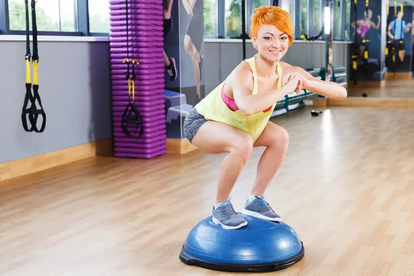 Athlétique fille est accroupi dans la salle de gym — Photo