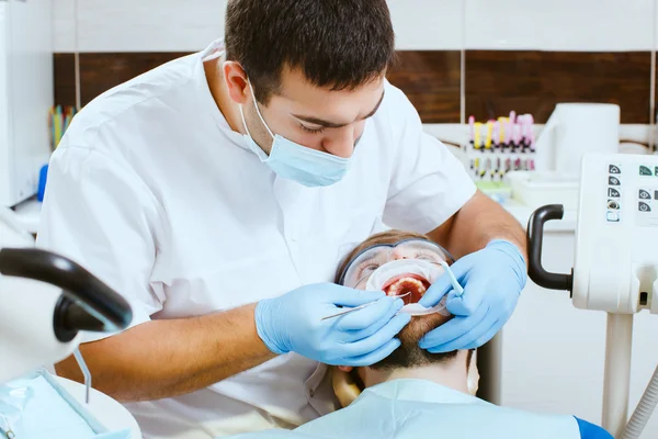 Dentysta bada zęby człowieka — Zdjęcie stockowe