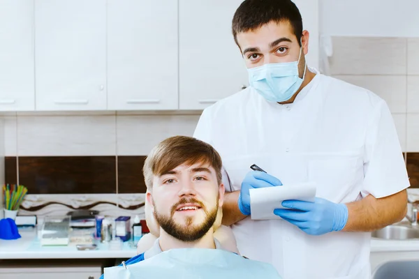 Стоматолог делает записи с пациентом, в стоматологическом кабинете . — стоковое фото