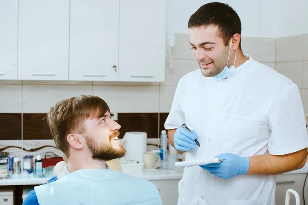 Dentista tomar notas com paciente feliz — Fotografia de Stock