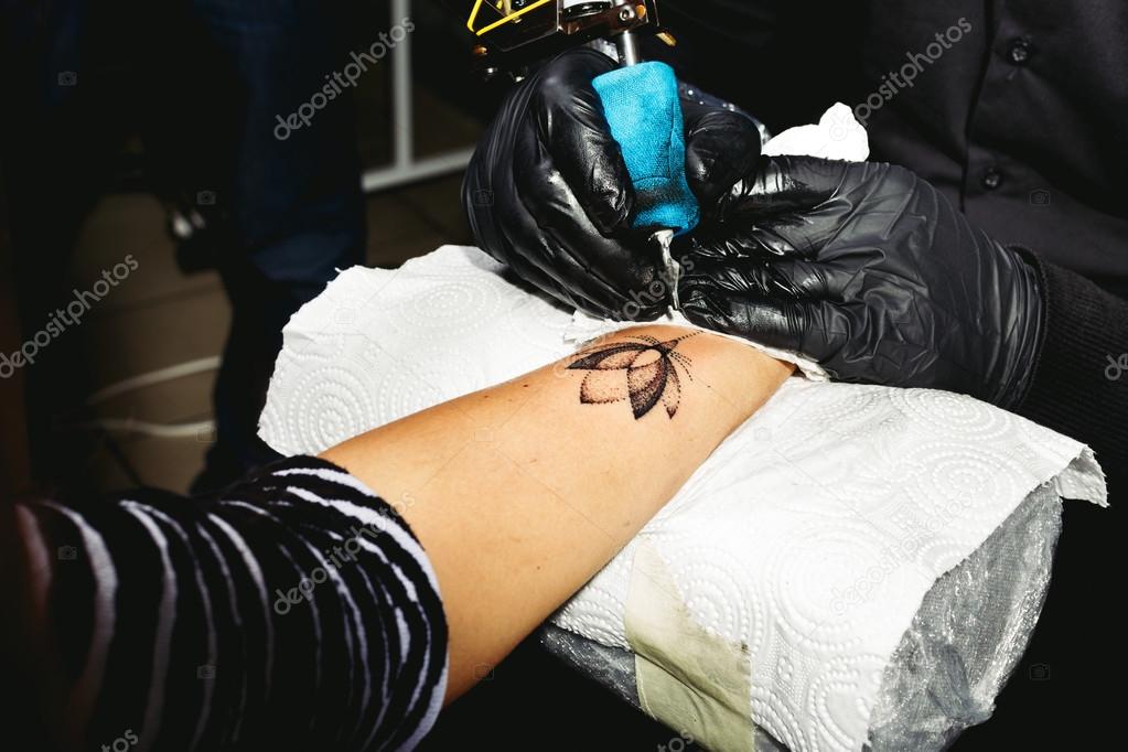 Tattoo artist works on the client's hand