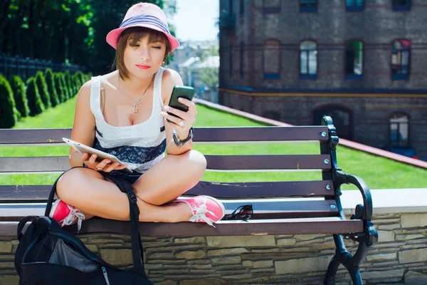 Frau sitzt mit Handy auf Bank — Stockfoto