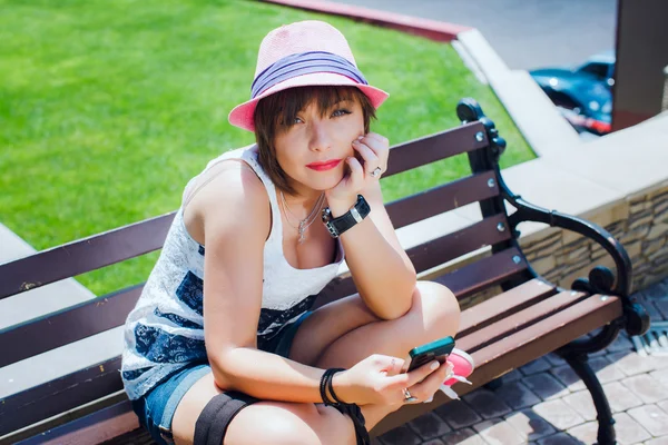 Женщина сидит на скамейке с мобильным телефоном — стоковое фото