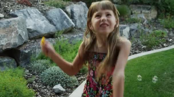 Dívka si hraje s mýdlovými bublinami v zahradě — Stock video