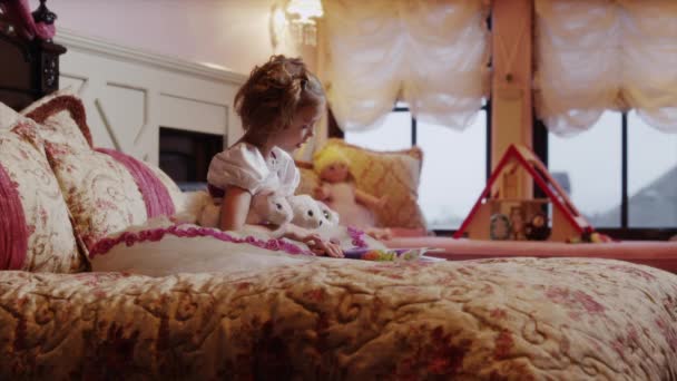 Fata citind carte pentru animale umplute pe pat — Videoclip de stoc