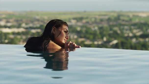Женщина отдыхает на краю бассейна — стоковое видео