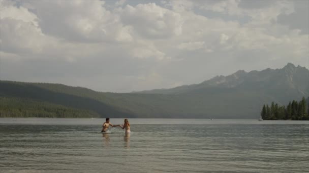 Pareja joven salpicando en el lago — Vídeos de Stock