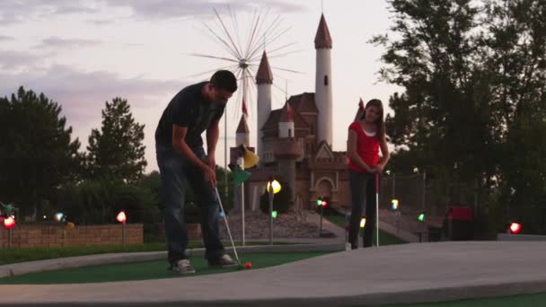Человек ставит на поле для мини-гольфа — стоковое видео