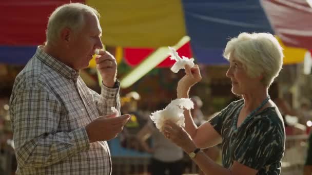 Старшая пара кормит друг друга сладкой ватой — стоковое видео