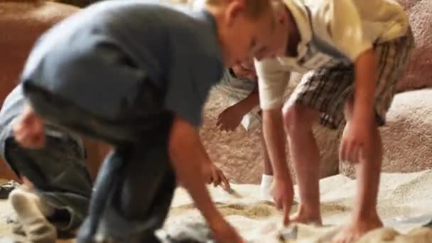 Jungen bürsten an Ausgrabungsstätte Sand aus Fossilien — Stockvideo