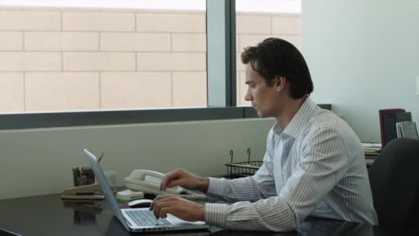 Бизнесмен с помощью ноутбука и телефона в офисе — стоковое видео