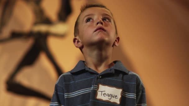 Скучный мальчик, смотрящий на скелет динозавра — стоковое видео