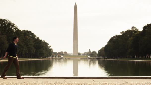 Family with children walking along reflecting pool — Stock Video