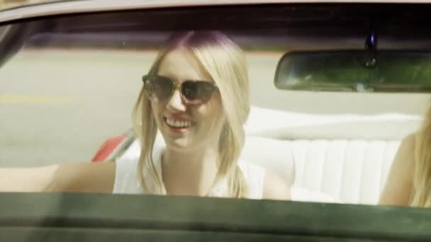 Mujeres saludando desde un coche descapotable — Vídeos de Stock