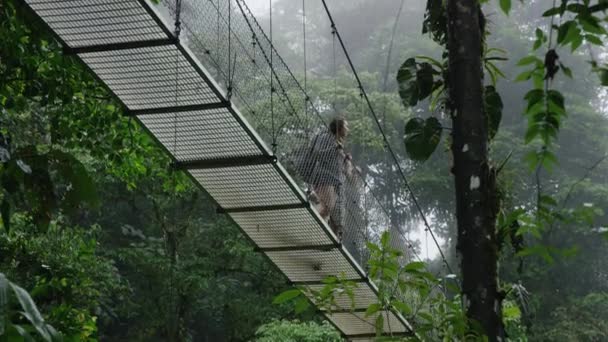 Casal atravessando ponte suspensa na selva — Vídeo de Stock