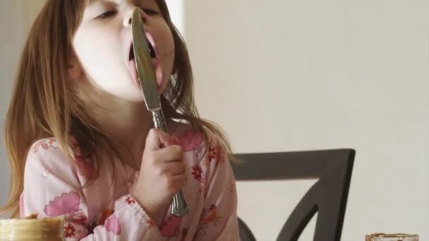 Menina lambendo faca na cozinha — Vídeo de Stock