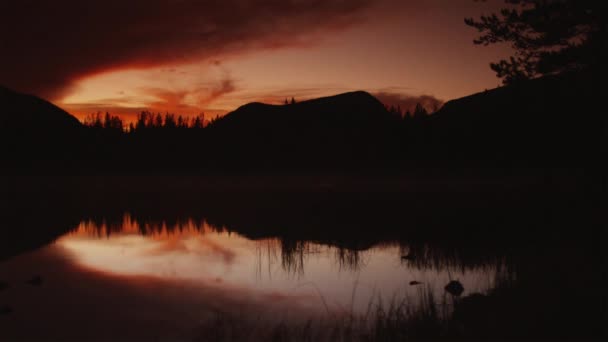 Jezioro otoczone wzgórzami na zachodzie słońca — Wideo stockowe