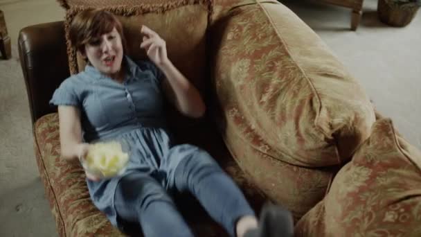 Vrouw die vallen op sofa potato chips eten — Stockvideo