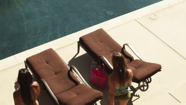 Mädchen im Bikini liegen auf Liegestühlen am Pool — Stockvideo