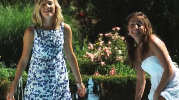 Женщина и девочка-подросток играют в фонтане — стоковое видео