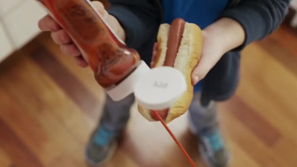 Хлопчик бризкає кетчуп на хот-дог — стокове відео