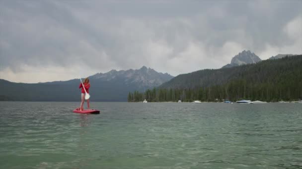 Młoda kobieta paddleboarding nad jeziorem — Wideo stockowe