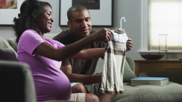 Жінка і чоловік дивиться на дитячий одяг — стокове відео
