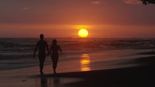 Gün batımında sahilde yürüyen çift. — Stok video