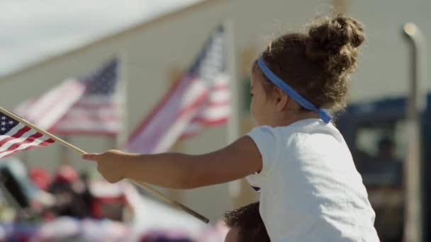 Девушка машет американским флагом на параде — стоковое видео