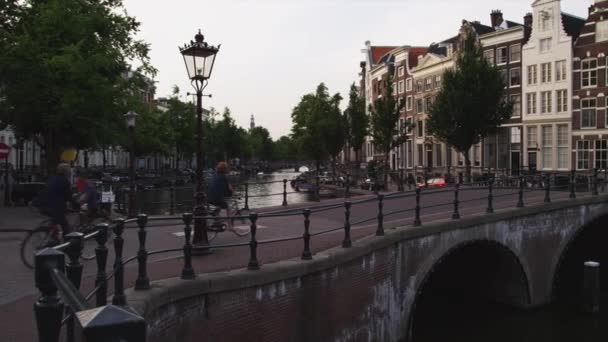 People on bicycles crossing bridge on canal — Stock Video